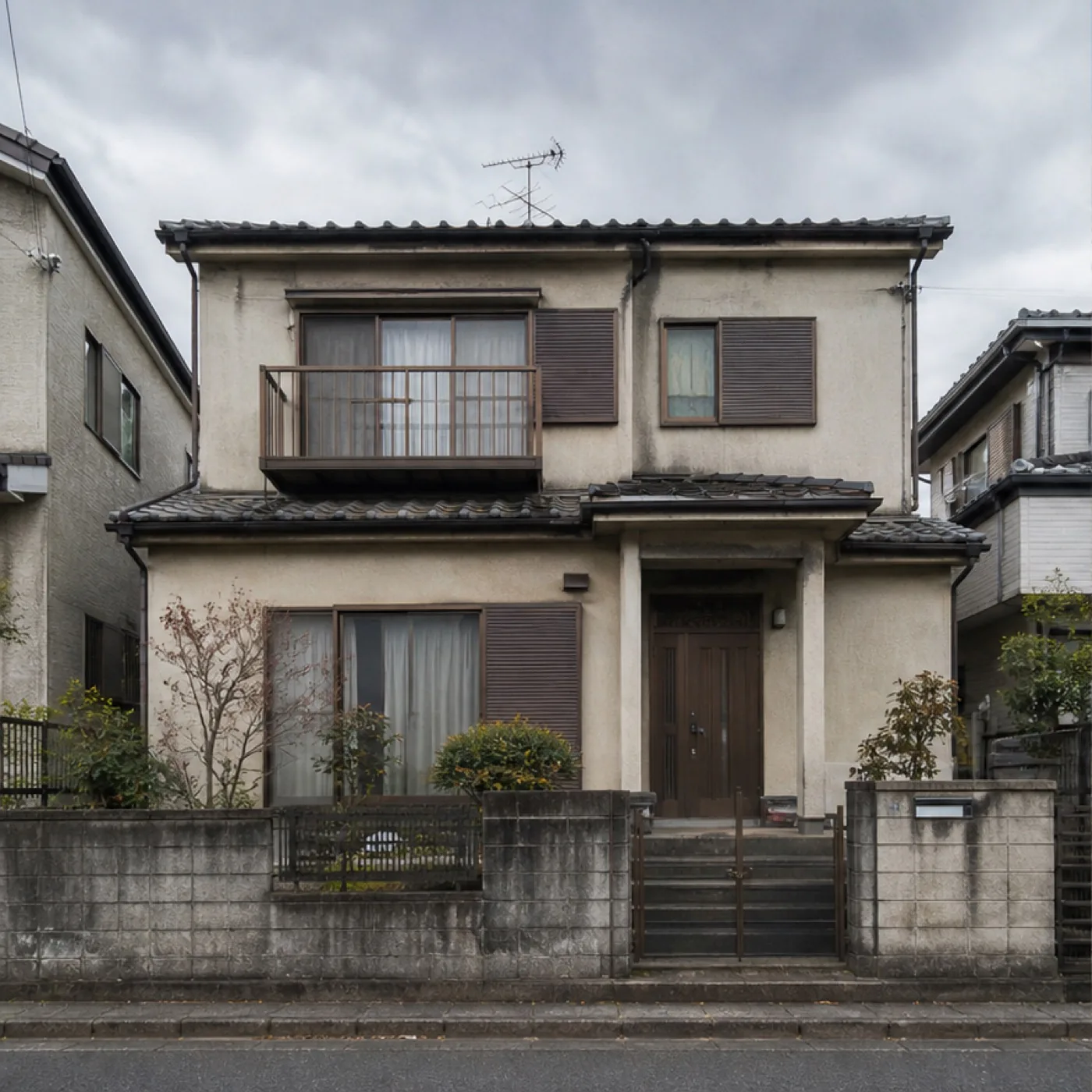 色あせ・ひび割れのある古い外壁と玄関